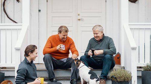 En familie som drikker kaffe og hygger med hund