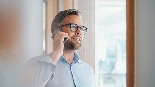 Mand i skjorte taler i telefon indenfor