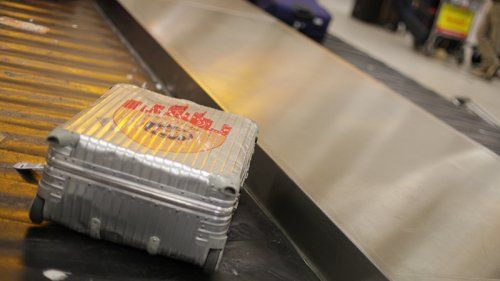 Sølv kuffert som ligger på et bagagebånd