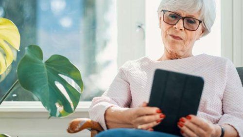 En kvinde sidder og læser på sin tablet