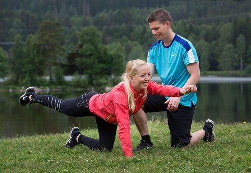 Mand og kvinde som laver styrkeøvelser på græsset