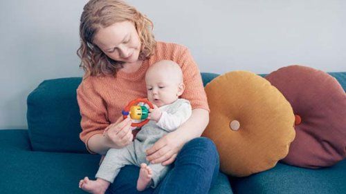 Mor med baby på skødet i sofaen hjemme