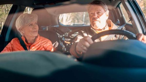 Middelaldrene par sidder på forsæderne af deres i bil - måske på vej på kør-selv-ferie.