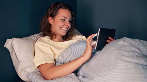 Yngre kvinde på sin Ipad i sengen