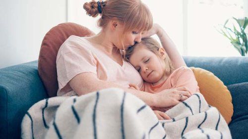 Mor holder om sin lille datter i sofaen