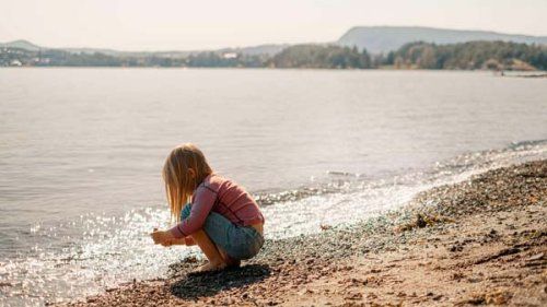 Rødhåret pige leger ved stranden en sommerdag.