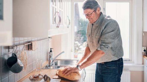 Mand i køkkenet som skærer brød