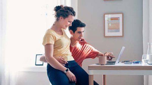 Ungt par sidder med computer hjemme i lejligheden