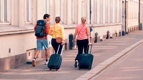 Tre venner på rejse med kufferter. Rejseforsikringen dækker også forsinket bagage
