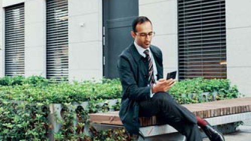 Mand sidder udenfor kontoret på sin mobil