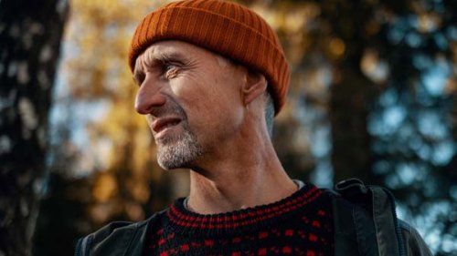 Mand iført orange hue og strikket sweater