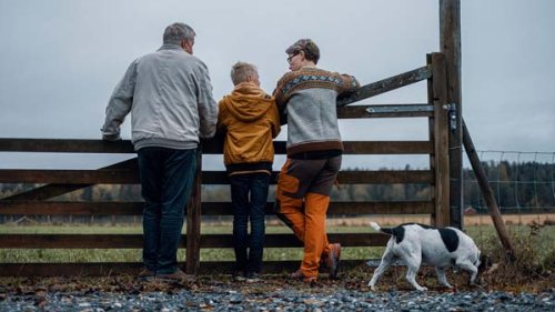 ældre mand, ung dreng, mor og hund står ved et hegn