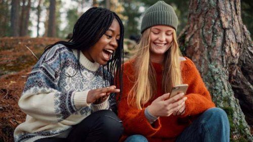 To piger er på telefonen selvom de er ude i naturen