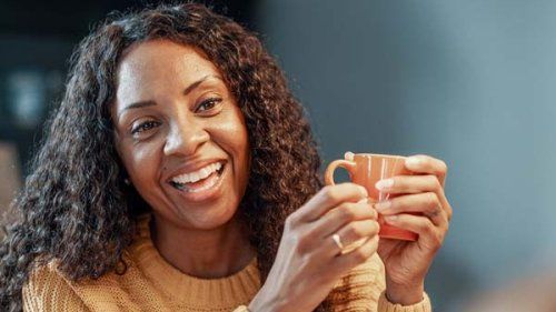 Kvinde med kaffekop der smiler