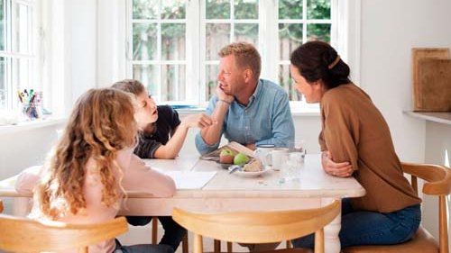 Mor og far og to børn sidder rundt om spisebordet.