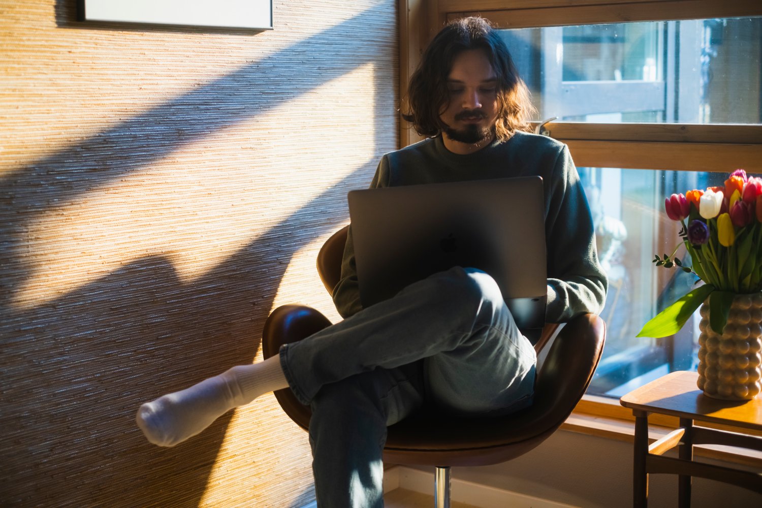 Ung mand sidder på en stol med sin computer